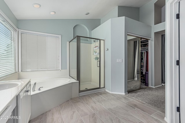 bathroom with a bath, a spacious closet, vanity, and a stall shower