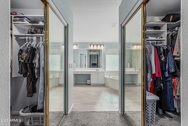 bathroom featuring visible vents, a spacious closet, a garden tub, and tile patterned floors