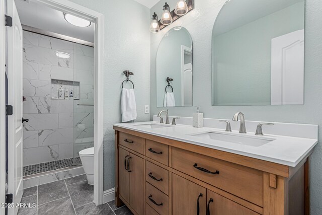 bathroom with marble finish floor, toilet, a sink, and tiled shower
