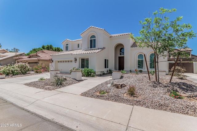 mediterranean / spanish home featuring stucco siding, a tile roof, a garage, and concrete driveway