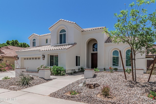 mediterranean / spanish home with a garage, a tile roof, concrete driveway, and stucco siding
