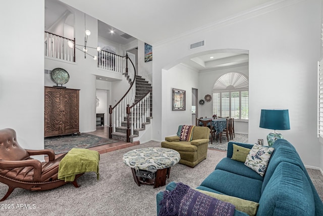 carpeted living area with arched walkways, baseboards, visible vents, stairway, and crown molding