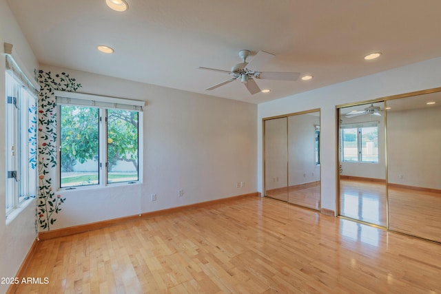 unfurnished bedroom with baseboards, multiple closets, and light wood-style floors