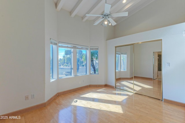 unfurnished bedroom featuring beamed ceiling, high vaulted ceiling, wood finished floors, a closet, and baseboards