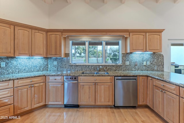 kitchen featuring stainless steel dishwasher, a high ceiling, stone counters, and a sink