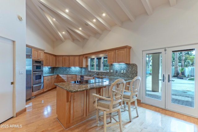 kitchen featuring dark stone countertops, high vaulted ceiling, a peninsula, appliances with stainless steel finishes, and a warming drawer