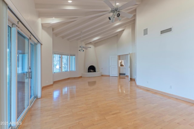 unfurnished living room featuring baseboards, beam ceiling, ceiling fan, and a fireplace