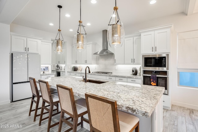 5901 E Sierra Morena St, Mesa, AZ 85215 - kitchen featuring tasteful backsplash, wall chimney exhaust hood, white cabinetry, stainless steel appliances, and light wood-style flooring