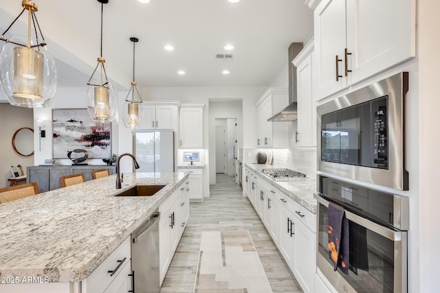 5901 E Sierra Morena St, Mesa, AZ 85215 - kitchen with visible vents, wall chimney range hood, a sink, light wood finished floors, and appliances with stainless steel finishes