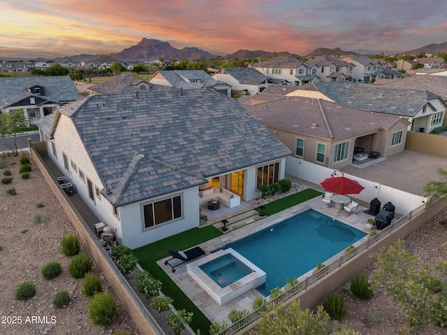 5901 E Sierra Morena St, Mesa, AZ 85215 - back of property at dusk with a residential view, a pool with connected hot tub, stucco siding, a fenced backyard, and a patio area