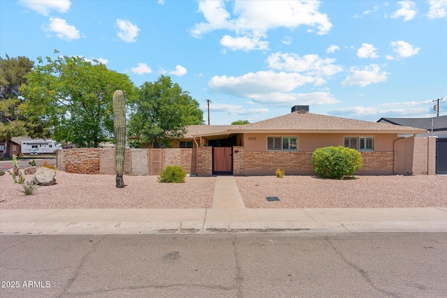 single story home with brick siding, a fenced front yard, stucco siding, and a gate