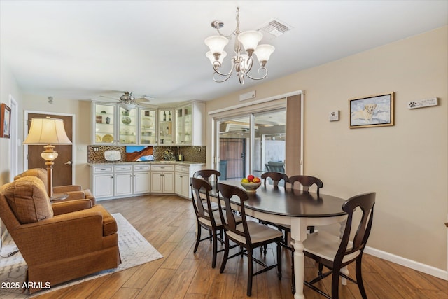 dining room with visible vents, light wood-style flooring, baseboards, and ceiling fan with notable chandelier