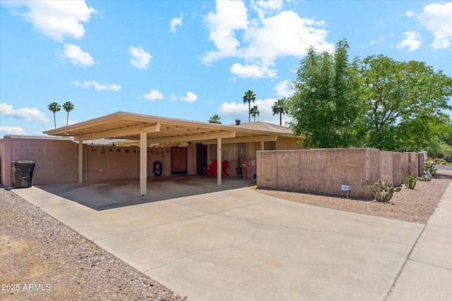 exterior space with fence, an attached carport, and driveway