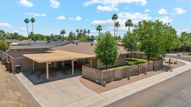 view of front of house featuring an attached carport, fence, and concrete driveway