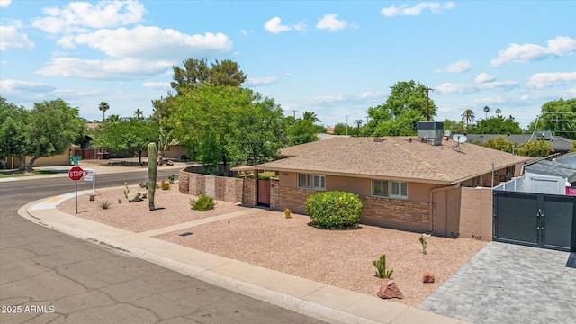 single story home featuring fence, cooling unit, brick siding, a gate, and roof with shingles