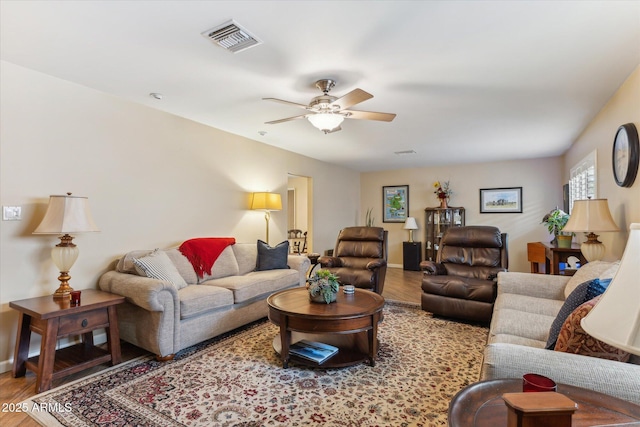 living room featuring visible vents, ceiling fan, baseboards, and wood finished floors