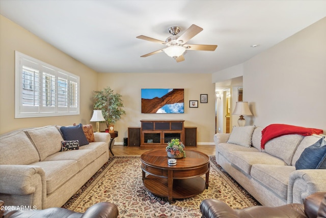 living room featuring baseboards, a ceiling fan, and wood finished floors