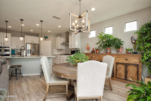 dining space featuring sink, light hardwood / wood-style flooring, and a notable chandelier