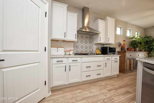 kitchen featuring white cabinets, wall chimney range hood, and light hardwood / wood-style flooring