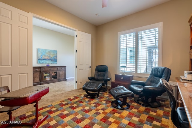 sitting room featuring a ceiling fan, carpet, and baseboards