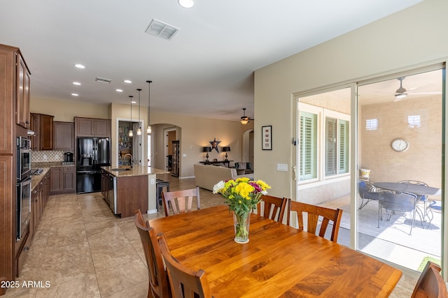 dining area with arched walkways, recessed lighting, visible vents, and a ceiling fan