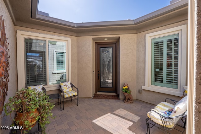 view of exterior entry with a patio and stucco siding