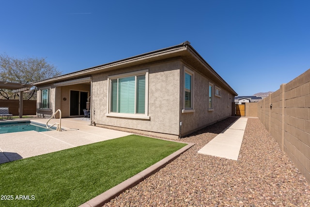 back of house with a patio area, a fenced backyard, a fenced in pool, and stucco siding