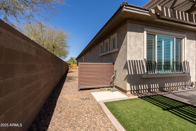 view of side of home with fence and stucco siding