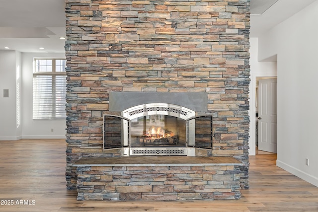 details featuring a stone fireplace, recessed lighting, wood finished floors, and baseboards