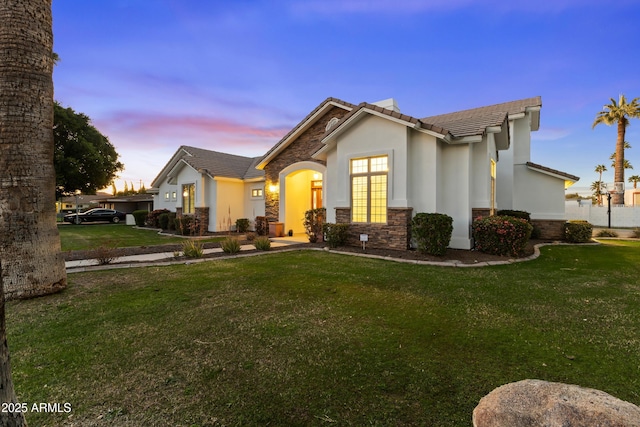 view of front of house featuring a front yard, stone siding, a tiled roof, and stucco siding