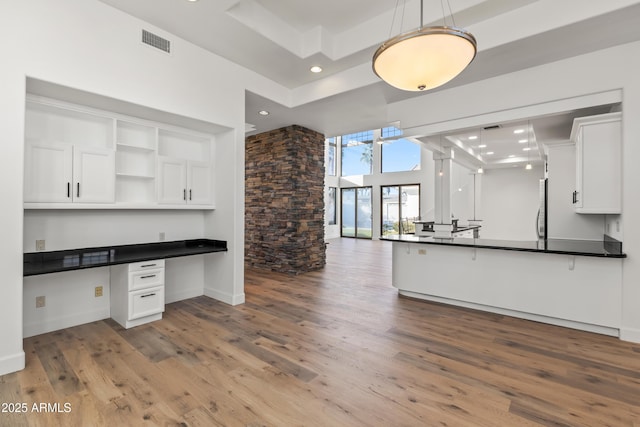 kitchen with visible vents, built in study area, dark countertops, white cabinetry, and open shelves