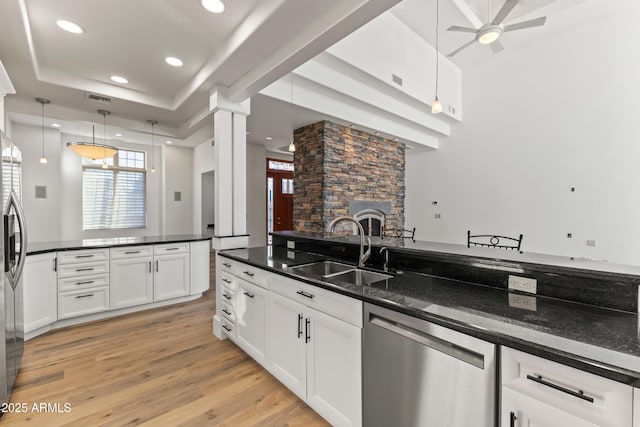 kitchen featuring decorative columns, light wood finished floors, appliances with stainless steel finishes, white cabinetry, and a sink