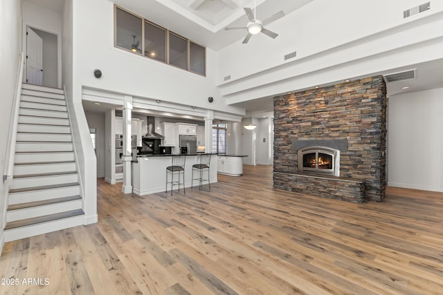 unfurnished living room with light wood-type flooring, visible vents, a fireplace, and stairway