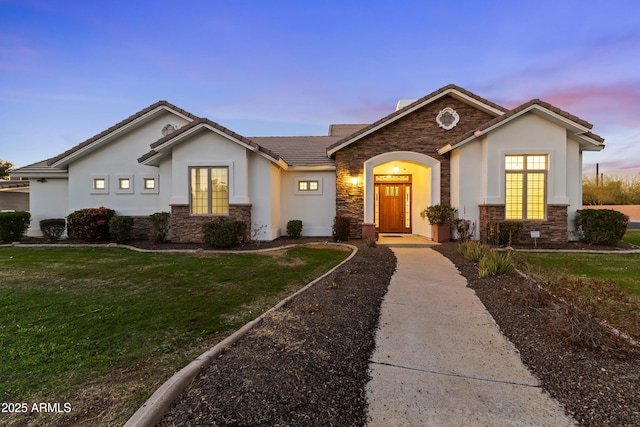 single story home featuring stone siding, a front yard, and stucco siding