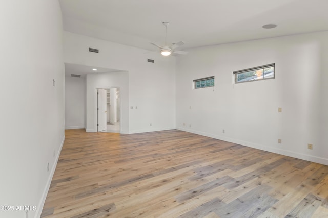 empty room with light wood-style floors, visible vents, baseboards, and a ceiling fan