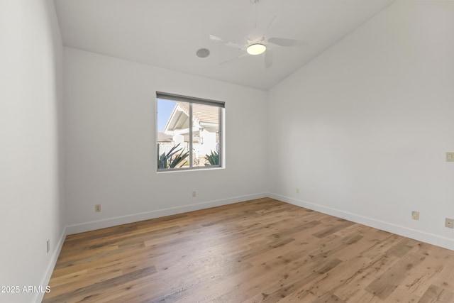 spare room featuring lofted ceiling, light wood finished floors, a ceiling fan, and baseboards