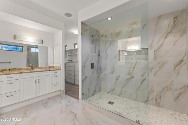 full bathroom with marble finish floor, vanity, a marble finish shower, and a spacious closet