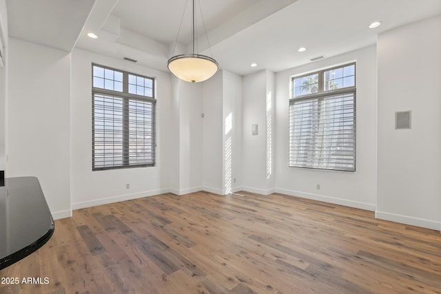 unfurnished room featuring visible vents, wood finished floors, a wealth of natural light, and baseboards