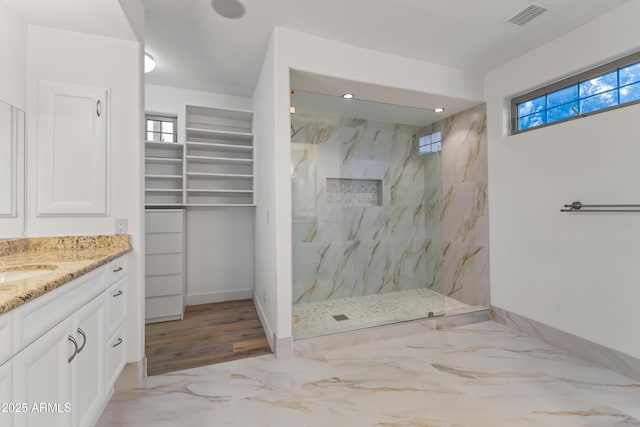 bathroom with plenty of natural light, a marble finish shower, visible vents, and vanity