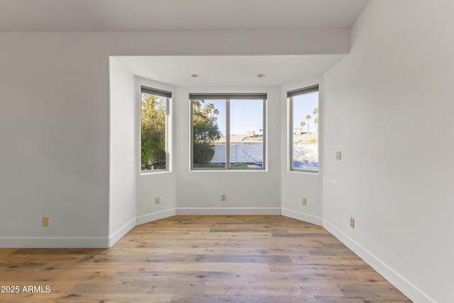 unfurnished room with light wood-type flooring and baseboards