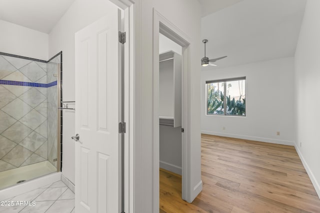 full bathroom featuring a shower stall, baseboards, ceiling fan, and wood finished floors