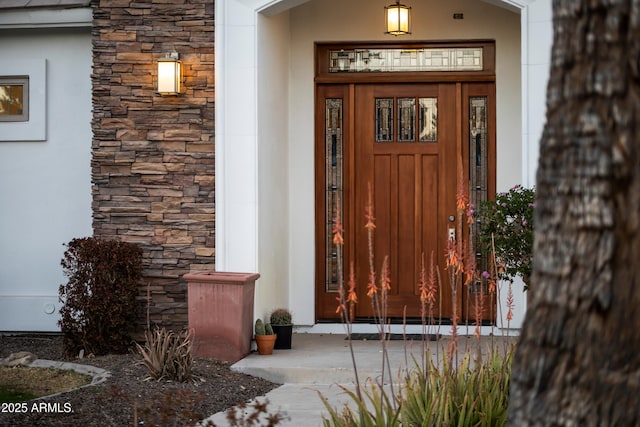 view of exterior entry featuring stone siding and stucco siding