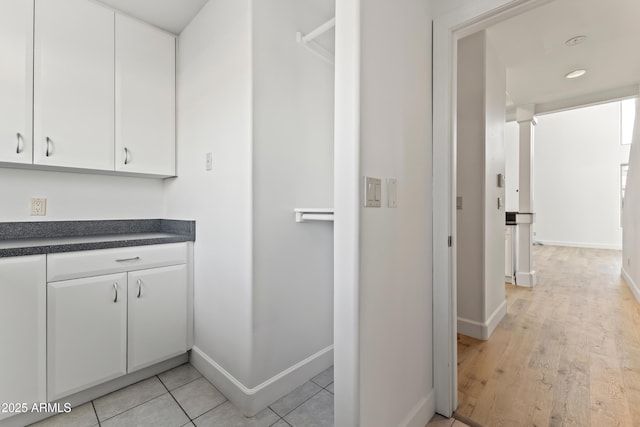 interior space with dark countertops, white cabinets, baseboards, and light tile patterned flooring