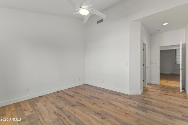 spare room featuring light wood finished floors, baseboards, visible vents, and a ceiling fan