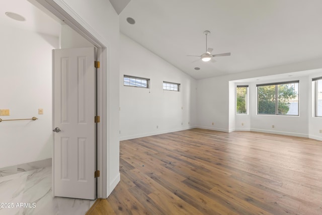 unfurnished room featuring ceiling fan, light wood-style flooring, baseboards, and vaulted ceiling