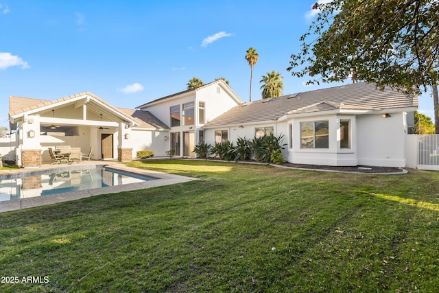 rear view of property with a yard, ceiling fan, a tiled roof, and a patio