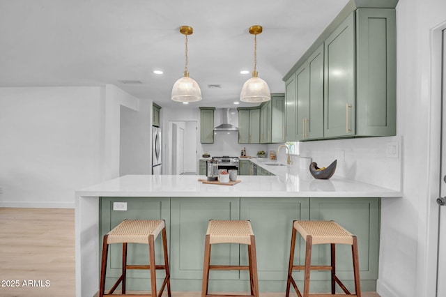 2712 N 20th Dr, Phoenix, AZ 85009 - kitchen featuring green cabinets, wall chimney exhaust hood, stainless steel appliances, a peninsula, and light countertops