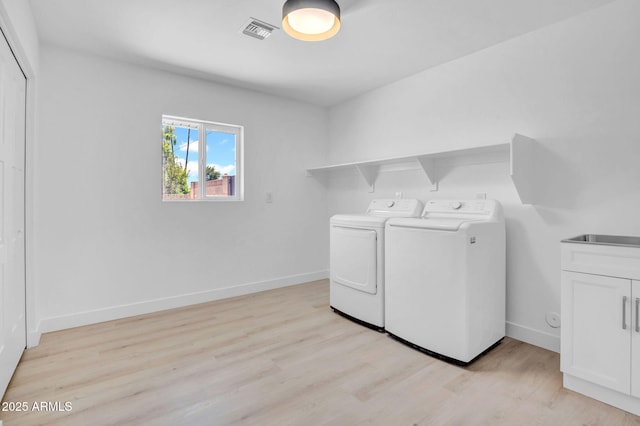 2712 N 20th Dr, Phoenix, AZ 85009 - washroom featuring washing machine and clothes dryer, cabinet space, and light wood-type flooring