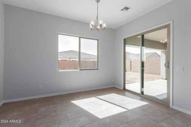 empty room with tile patterned floors and an inviting chandelier