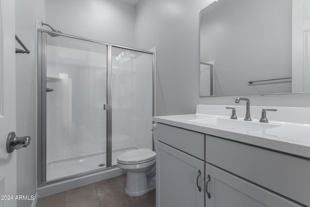 bathroom featuring tile patterned floors, toilet, vanity, and a shower with shower door